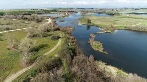 Aerial view of the San Joaquin River winding past green banks and gravel trails