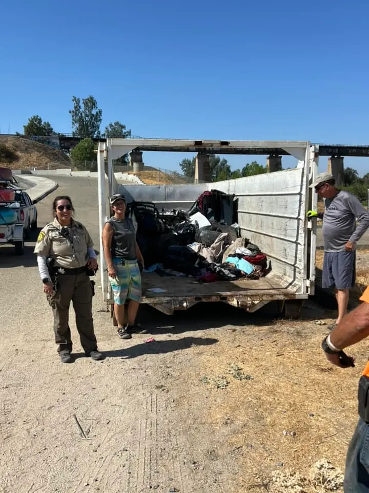 Volunteers and a park ranger beside a dumpster loaded with debris cleared from the river bottom