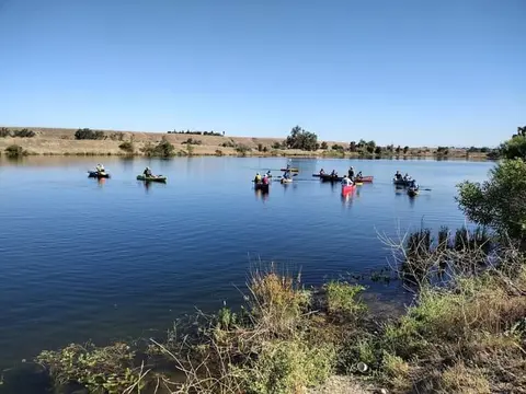 A flotilla of canoes spread across calm blue water