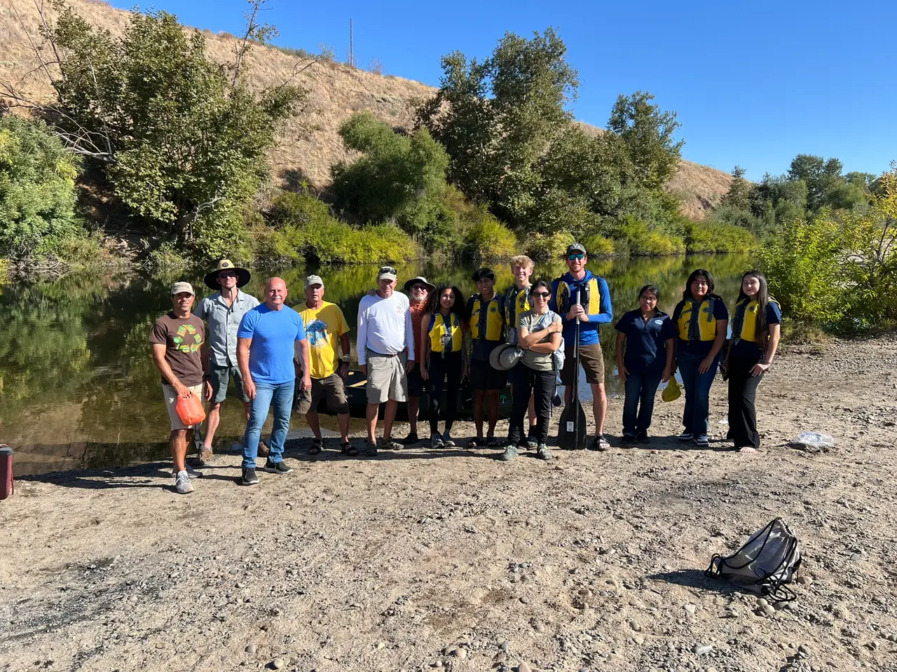 River Tree volunteers of all ages, many in yellow life vests, gathered on the bank of the San Joaquin River