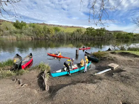 Volunteers launching canoes from a green riverbank in early spring