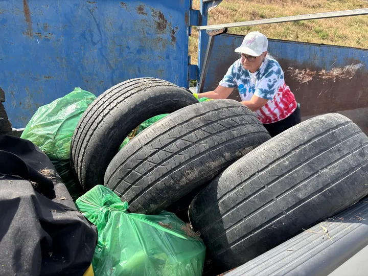 A volunteer loading tires hauled out of the river into a debris bin
