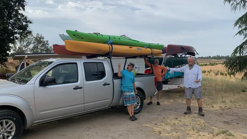 Volunteers beside a pickup loaded with kayaks and canoes, ready to head out