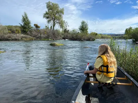 A young volunteer in a life vest watching the river from a canoe